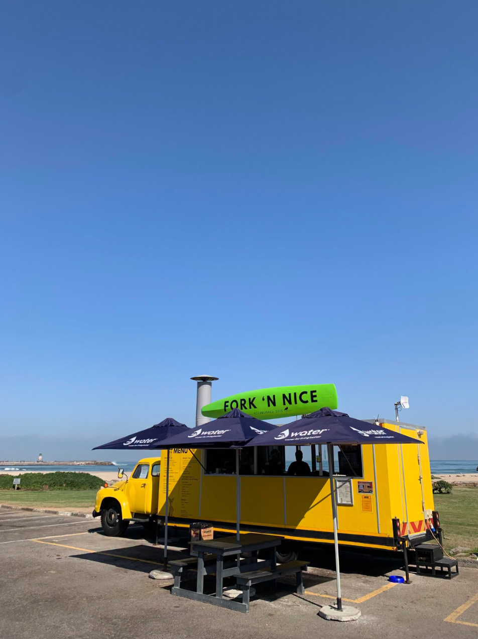 The Fork n Nice yellow food truck with navy umbrellas on the Swakopmund beachfront